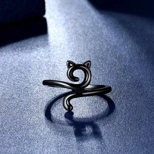 Macro shot of minimalist black cat ring with cute ears and tail on textured background