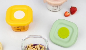 Assorted baby food glass containers with colorful silicone lids and scale markings