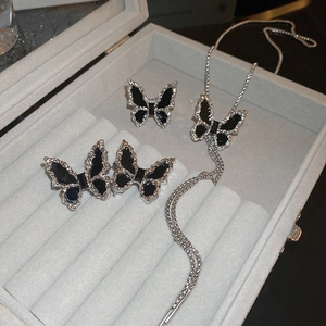 Detail of silver butterfly jewelry set with black enamel in a grey velvet gift box