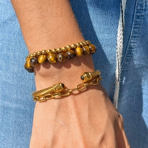 Ensemble bracelet câble doré et perles œil de tigre sur fond denim style de vie