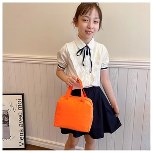 Girl carrying an orange insulated lunch bag against a minimalist white interior wall