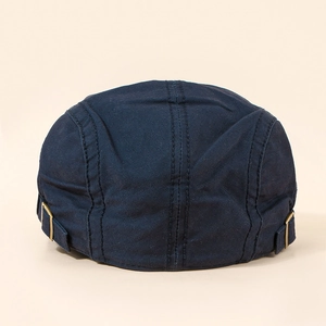 Detail view of adjustable bronze metal buckles and twill fabric texture on a flat cap