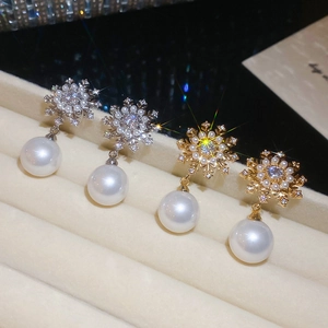 Macro shot of snowflake earrings with sparkling zircons and large white pearls