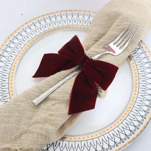 Dark red velvet bow napkin ring decoration on a silver fork with linen napkin