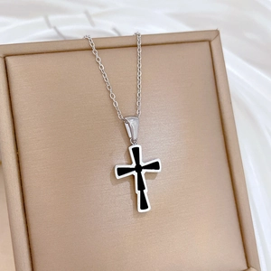 Detail shot of a silver titanium steel cross pendant necklace inside a beige jewelry box