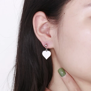 Close-up of a silver heart-shaped earring worn by a model with a polished mirror finish