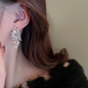 Elegant silver leaf dangle earrings with marquise-cut zircons worn by model