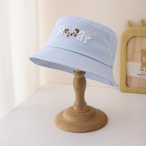 Détail d'un chapeau bob enfant en coton bleu clair avec broderie ours et lettrage