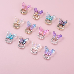 Macro shot of colorful 3D resin butterfly nail charms with rhinestones on pink background