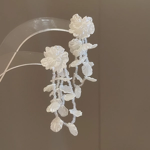 Detailed close-up of white chiffon flower earrings with elegant long bead tassels
