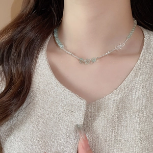Detailed view of handmade light green beaded necklace with silver accents on a model