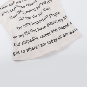 Detailaufnahme des cremefarbenen Strick-Tops mit feiner Textur und schwarzem Buchstabendruck