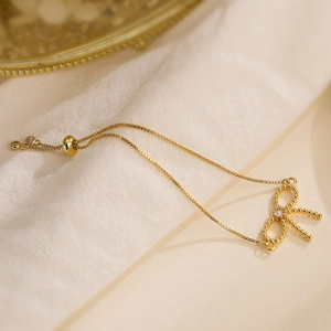 Detail of gold bow charm bracelet with zircon stones and adjustable sliding clasp