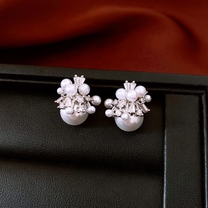 Macro shot of silver pearl studs with zircon stones on a black leather texture base