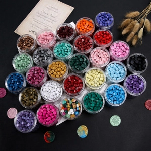 Various colors of octagonal sealing wax beads in clear jars with vintage dried flowers