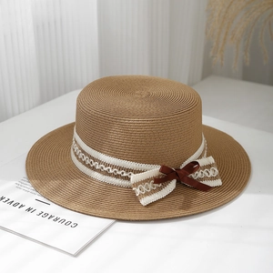 Detailed macro of woven straw boater hat featuring elegant white lace bow and silk ribbon