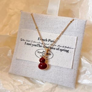 Vue détaillée du collier plaqué or avec pendentif gourde rouge et zircons étincelants