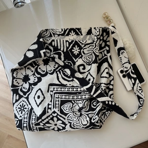 Flat lay of a bohemian black and white patterned linen tote bag with long straps