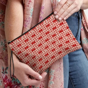 Pochette per trucco portatile a scacchi con ciliegie e manico nero tenuta dal modello
