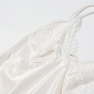Detailed view of white silk slip dress featuring delicate lace stitching at the neckline