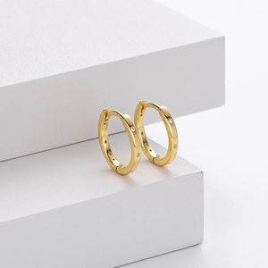 Macro detail of gold S925 sterling silver huggie earrings with clear cubic zirconia stones