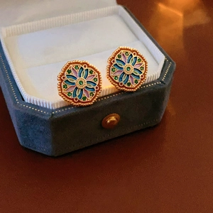 Close-up of vintage gold floral earrings with colorful enamel in a velvet jewelry box