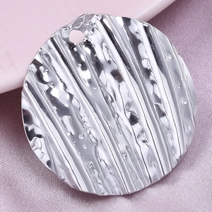 Macro shot of silver 304 stainless steel round pendant with hammer and stripe texture