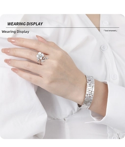 Detailed close-up of diamond-set floral silver ring and textured bracelet set on a model