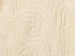Vue macro du tissu crème avec motifs de broderie en spirale finement détaillés
