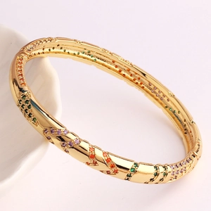 Detailed shot of gold plated bracelet with colorful rainbow cubic zirconia on ceramic tray