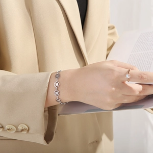 Detail showing elegant silver hollow round link bracelet and gemstone ring on model