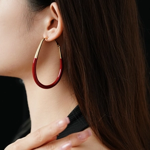 Close-up of a model wearing a large red and gold enamel hoop earring in high detail