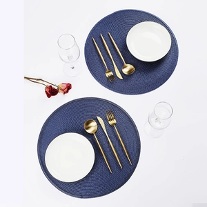 Overhead view of blue round woven placemats with gold cutlery and white ceramic plates