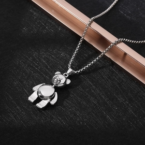 Macro shot of a silver teddy bear pendant on a box chain over a dark background
