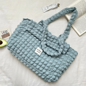 Close-up of light blue bubble textured canvas tote bag with studio brand label on fabric