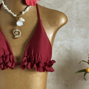 Detail of wine red bikini top with ruffled edges and halter neck on a display mannequin