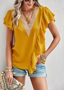 Detail of yellow V-neck blouse featuring delicate white lace trim and ruffled edges