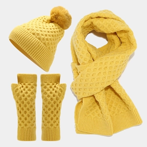 Flat lay of yellow honeycomb knit winter set including pompom hat, scarf, and fingerless gloves