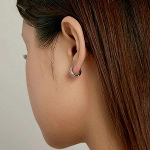 Close-up of silver pave-set hoop earring with crystals on a woman's ear