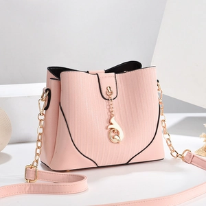 Pink minimalist crossbody bag with gold chain strap and vertical texture on white stand