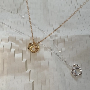 Flat lay of gold and silver heart-shaped necklaces on white textured paper background