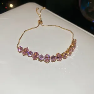 Bracelet doré en zircon rose avec chaîne réglable et pierres ovales sur support blanc