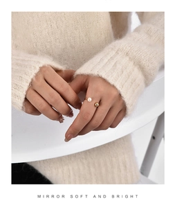 Elegant gold open ring featuring a white pearl and metallic bead on a model's hand
