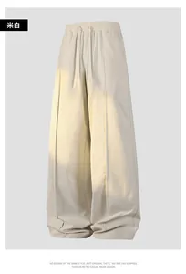 Detail of off-white wide-leg trousers with drawstring waist and sharp front pleat design