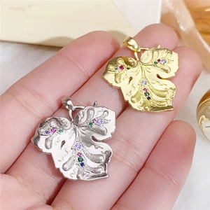 Macro detail of leaf-shaped copper pendants with multicolored zircons in gold and silver
