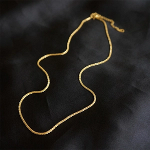 Elegant gold twisted chain necklace displayed on a luxury black silk textured background