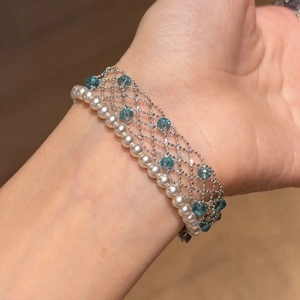 Close-up of woven pearl and blue crystal bead bracelet on a female model's wrist