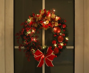 Festive Christmas wreath with red berries and LED lights hanging on a dark window