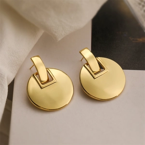 Macro shot of gold geometric matte earrings on white fabric with minimalist lighting