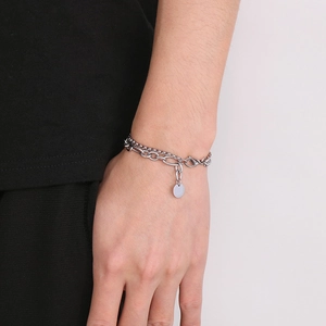 Detail of silver double-layered stainless steel bracelet with a round charm on wrist